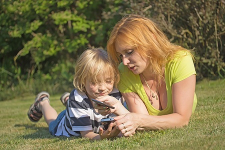 Mother showing her son how to use a smart phone.の写真素材
