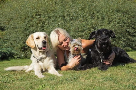 Blond woman is lying with three dogs at the lawn.の写真素材