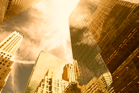 View of Manhattan skyscrapers from whose walls are reflected clouds in the sky  Golden color の写真素材