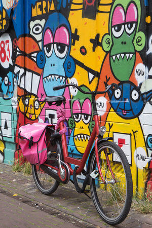 The bicycle leaning against a wall painted with color pictures and inscriptions   Amsterdam, Netherlands   All potential trademarks are removed のeditorial素材