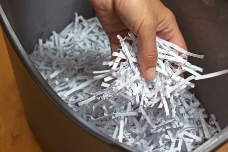 Hand holding shredded paper strips in a basket shreddersの写真素材