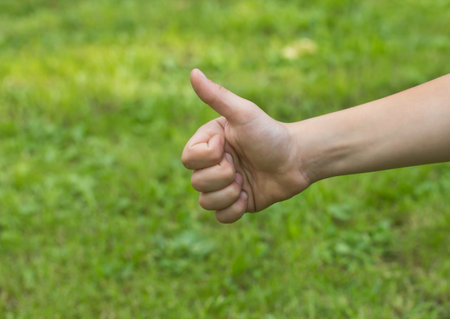 The children's hand is showing Number one. Outdoors with green background.の写真素材