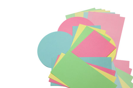 Rectangular and circular yellow, blue, red and green colored papers are spread out on an isolated...