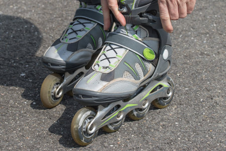 Closeup view of a woman putting on her rollerblades outdoors. All potential trademarks are removed.