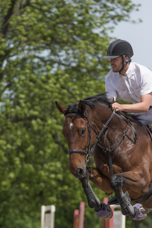 TRESTINA, CZECH REPUBLIC - MAY 16: Closeup of horseman in white that is jumping on the brown horse at "Equestrian Hobby Series 2015" on May 16, 2015  in Trestina, Czech Republic.のeditorial素材