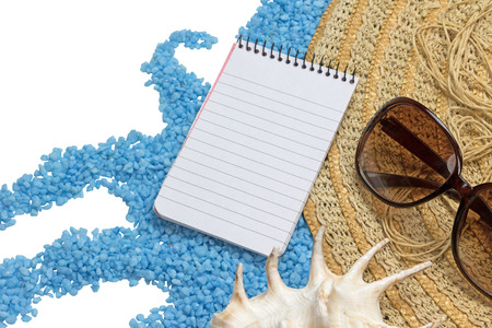 Straw hat, sunglasses, paper notebook and a seashell are lying on a little blue stones forming a wave isolated on the white.の写真素材
