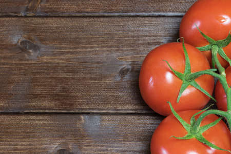 Tomatoes are lying on a wooden board in the right edge of the photo.の写真素材