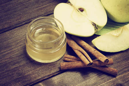 Aerial view of a green apples sliced, a jar of honey and a cinnamon lying on a wooden table. Photo is edited as a vintage with dark edges.の写真素材