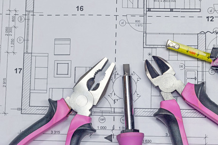 Screwdriver, tape measure, combination pliers and diagonal cutting pliers with pink design are lying on the blueprint background. All potential trademarks are removed.の写真素材
