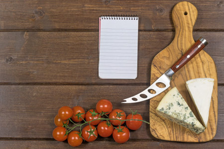 Cheese with white mold it and stainless steel cheese knife with wood handle are is lying on the...