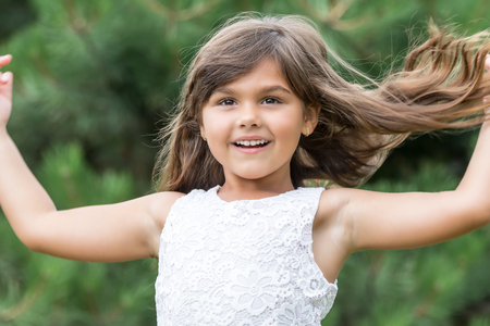 Portrait of cool smiling little girl with flowing hair outdoors.の写真素材