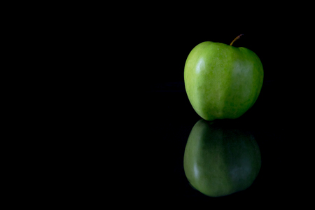 Low key picture of reflecting a green apple on a black background.の写真素材