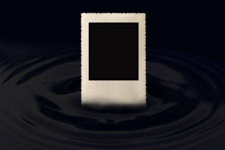 Front view of an old vintage photo frame with jagged edges partially submerged in the water, which...