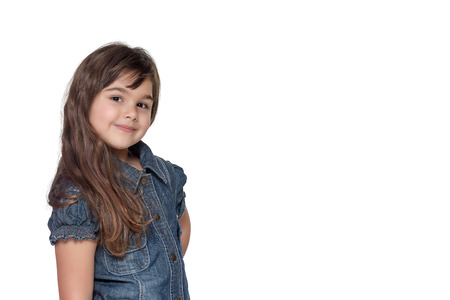 Portrait in half of the body of long haired brunette little girl isolated on the white background. Girl is standing sideways and is looking at the camera.の写真素材