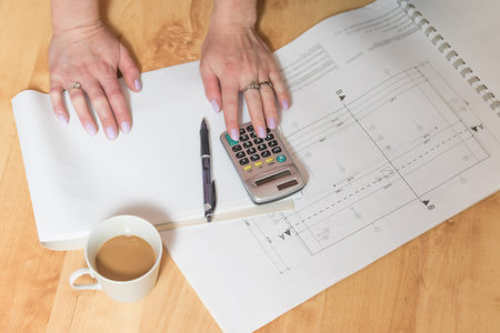 Construction and housing concept. Female hands  working for new project plan lying on the wooden...