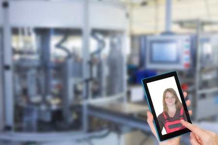 Female is using the smart phone with photo of female worker in overall on the screen. Blurred ...