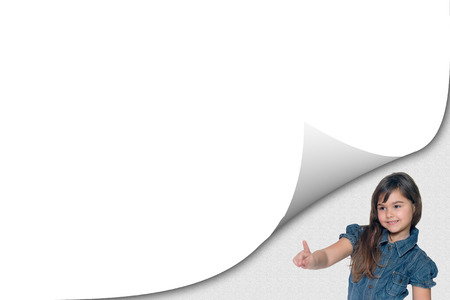 Cute tanned little girl is pointing at a blank page with curl effect ready for your text.の写真素材