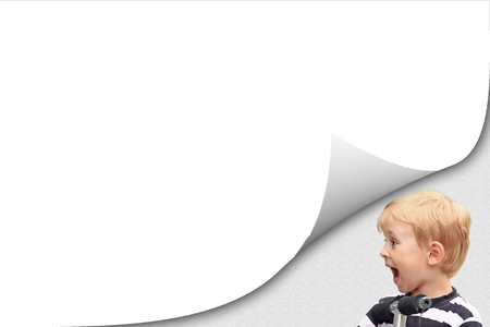 Blank white page with curl effect and surprised blond boy in the striped shirt on a scooter in an exposed corner. Blank paper list is ready for your text.の写真素材