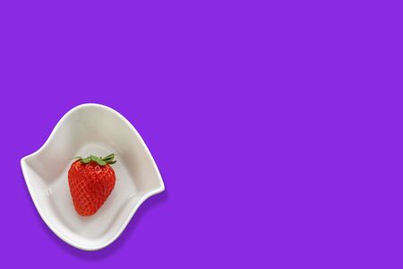 Strawberry in a white bowl on a neon purple color background  There is enough space in the photo for your use.の写真素材