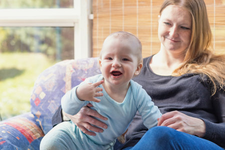 Smiling toddler together with her mother. The baby is looking at the camera.