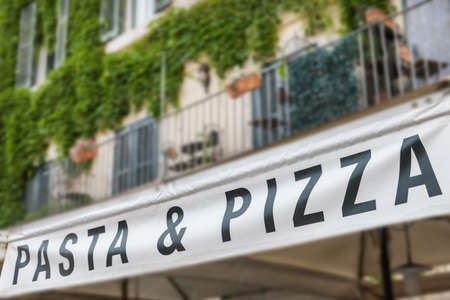The Pasta and Pizza sign on old intentionally blurred  house with balcony and plants in pots.の写真素材