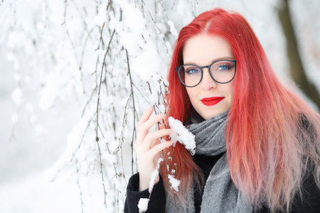 Smiling attractive red hair girl in glasses posing in wintry nature.の写真素材