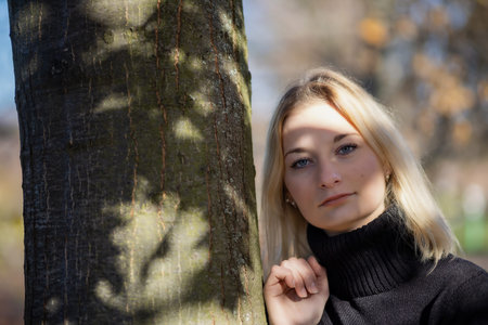 Long hair girl is looking at the camera in autumn park. Horizontally.