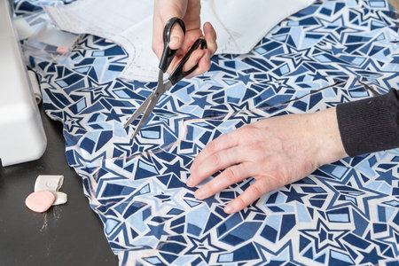 Top view of woman's hands cutting fabric.. Horizontally.