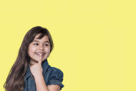 Smiling cute tanned little girl is on the yellow background ready for your text.の写真素材