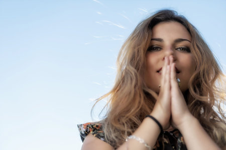 Bottom view of atractive young woman posing  against blue sky. Horizontally.