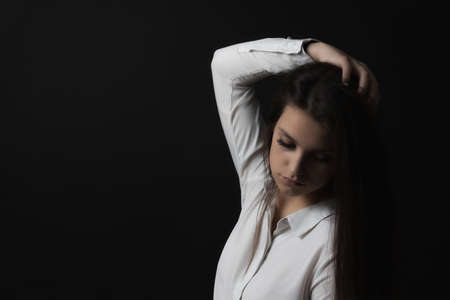 Low key portrait of sad young woman weared in white shirt.の写真素材