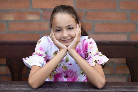Pretty little girl  is smiling at the camera. Brick wall is in the background. Horizontally.の写真素材