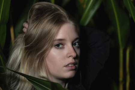 Blonde young woman is running her hands through her hair outdoors. Horizontally.