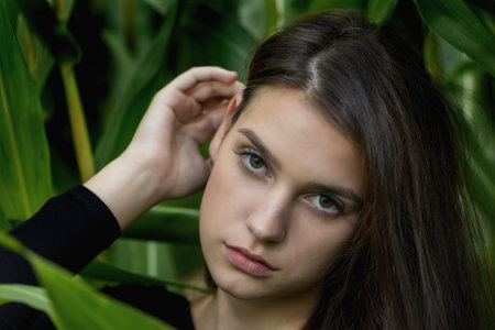 Closeup portrait of brunette young woman posing among the green plantsの写真素材
