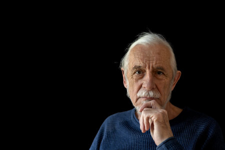 Beautiful gray hair old man wirh wrinkled face is posing on black background looking at the camera.の写真素材