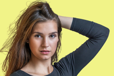 Portrait of beautiful long haired girl posing on yellow  background.  Horizontally.の写真素材