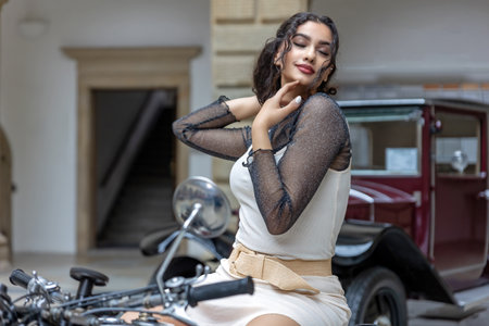 Young woman with long black  hair is sitting seductively on a vintage motorcycle. Horizontally.の写真素材