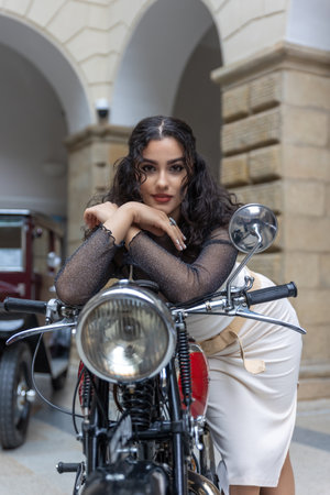 Sexy young woman is posing on a vintage motorcycle  looking at the camera. Vertically. .の写真素材