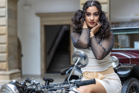 Attractive young woman sitting on a vintage motorcycle.  Horizontally.の写真素材