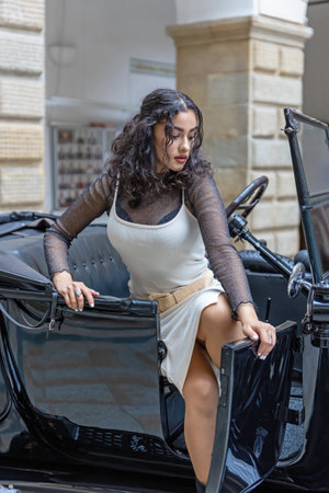 Attractive young woman is getting out of the vintage car. Vertically.の写真素材