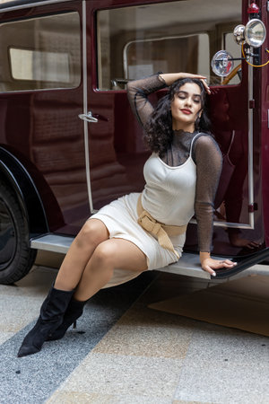 Relaxed sexy young woman is posing on a vintage car. Vertically.の写真素材