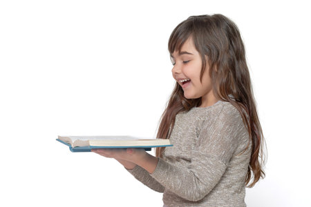 Side view of cute long haired tanned girl laughing over open book in her hands. Free space for your text.の写真素材