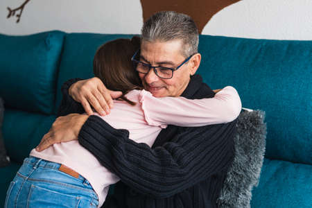 Grandfather sadly hugs his granddaughter who is crying inconsolably, to calm her discomfort.の写真素材