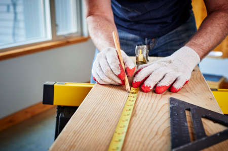 a man using a tape measure and pencilの写真素材