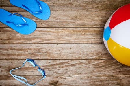 a beach ball goggles and sandals on a dockの写真素材