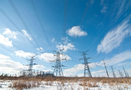 A long line of electrical transmission towers carrying high voltage lines.の写真素材