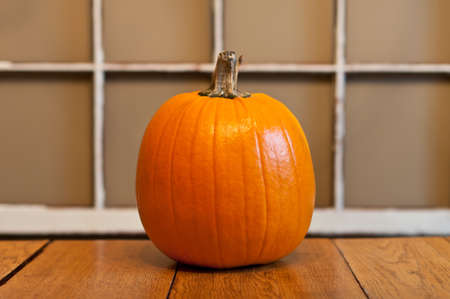 An orange pumpkin sits on a wooden table.の写真素材
