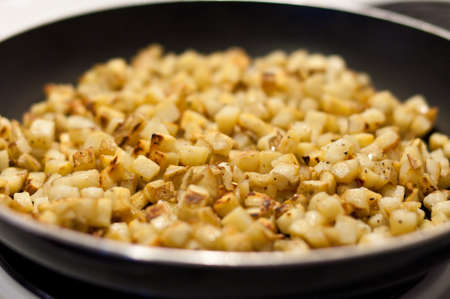 Diced potatoes fry in a pan with pepper and olive oilの写真素材