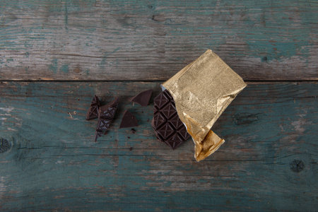 Dark chocolate wrapped in gold foil, on old, vintage table, stock photoの写真素材