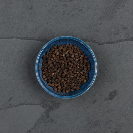 Small bowl of pepper corns, on a grey slate tableの写真素材
